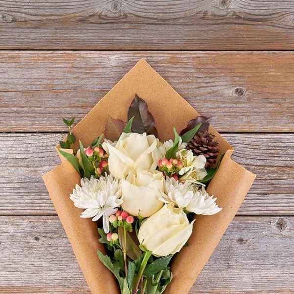 Snowcap Bouquet comprises of mums and roses with pinecones, berries and eucalyptus.