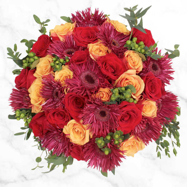 The warm wishesh Bouquet includes bicolor yellow roses, purple spider gerberas, eucalyptus and green fillers